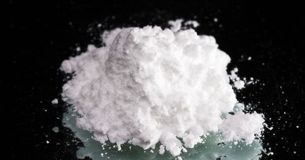 Cocaine drugs heap on a black mirror, close up view