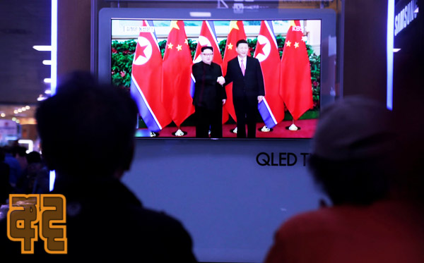 People watch a TV news report about the meeting between North Korean leader Kim Jong Un and Chinese President Xi Jinping at a railway station in Seoul
