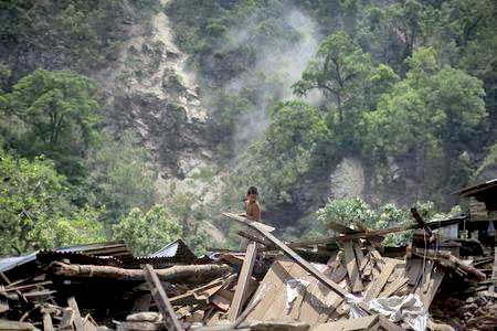 A boy clears rubble from his home during a landslide after Tuesday's earthquake at Singati Village, in Dolakha, Nepal