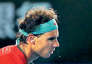 Drops of sweat fall from Nadal of Spain as he serves to Federer of Switzerland during their men's singles semi-final match at the Australian Open 2014 tennis tournament in Melbourne