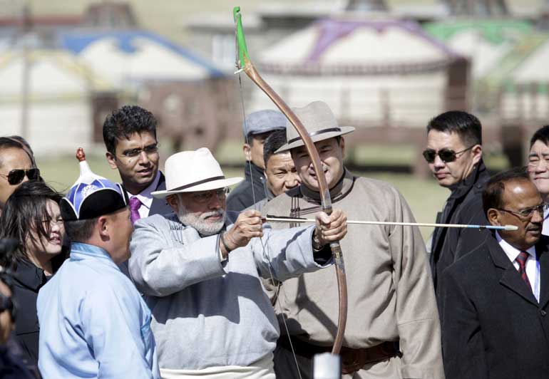 India's PM Narendra Modi draws a bow next to his Mongolian counterpart Chimed Saikhanbileg as they attend a Naadam festival celebration on the outskirts of Ulan Bator, Mongolia