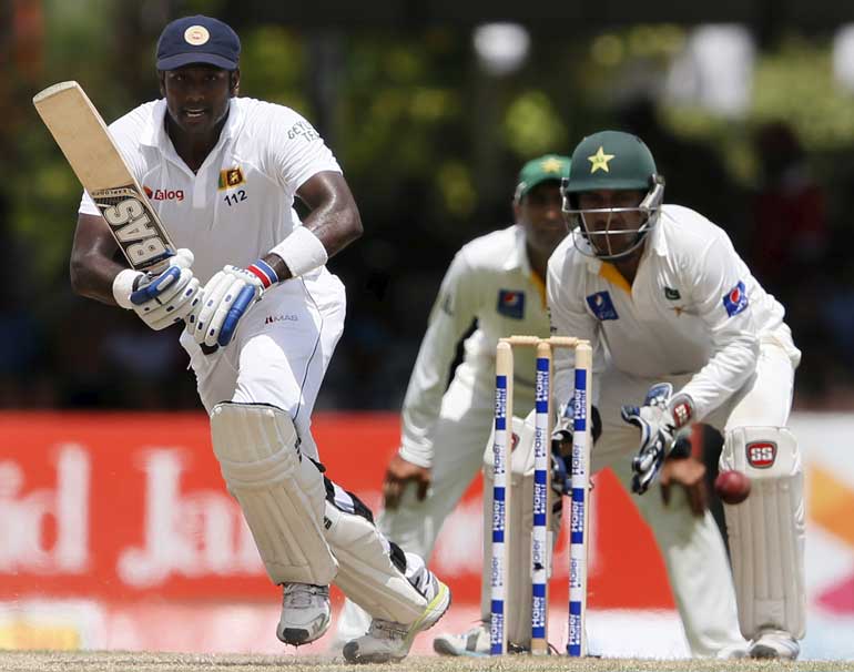 Sri Lanka's captain Mathews plays a shot next to Pakistan's wicketkeeper Ahmed during the second day of their second test cricket match in Colombo