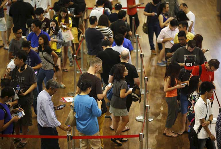 People queue up to buy Apple watches outside an Apple reseller shop in Singapore