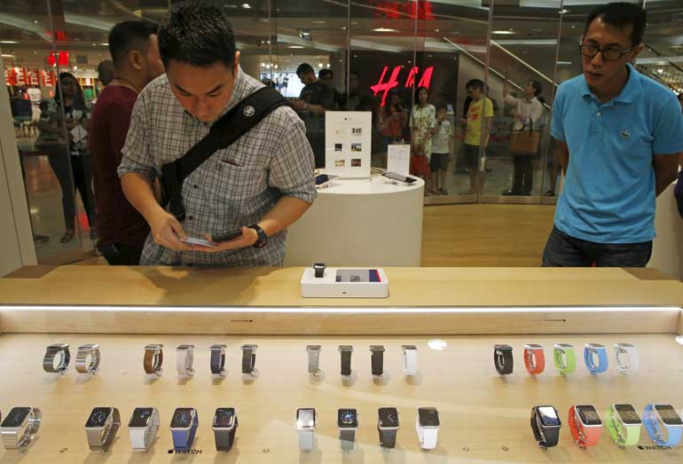 People look at Apple watches while others queue up to buy Apple watches at an Apple reseller shop in Singapore