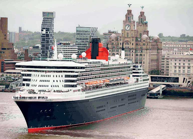 The Cunard liner Queen Mary 2 performs a turn in front of the Liver buildings on the River Mersey in Liverpool