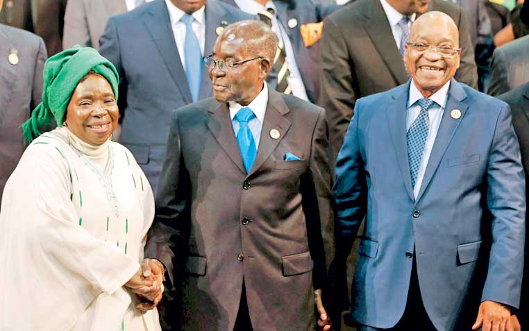 Chairperson of the African Union (AU) Commission Nkosazana Dlamini-Zuma smiles as she is greeted by Zimbabwe's President Robert Mugabe next to South Africa's president Jacob Zuma ahead of the 25th African Union summit in Johannesburg