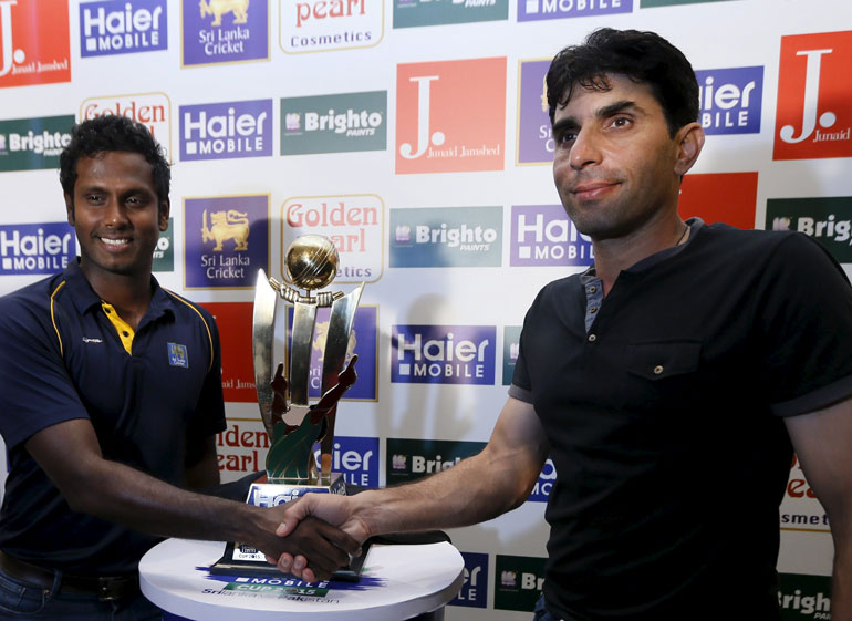 Sri Lanka's cricket captain Angelo Mathews (L) and his Pakistani counterpart Misbah-ul-Haq shake hands next to the series trophy during a news conference in Colombo