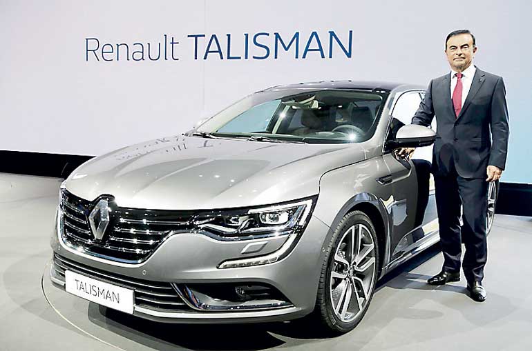 Carlos Ghosn, CEO of the Renault-Nissan Alliance, poses next to the new Renault's new D-segment saloon Talisman after its unveiling during a press event at the Chateau de Chantilly near Paris