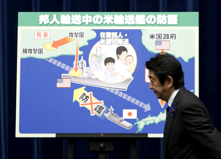 File photo of Japan's PM Abe arrives at a news conference in front of a placard showing a defensive scenario for the protection of Japanese nationals overseas, at his official residence in Tokyo