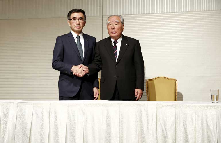 Suzuki Motor's new President Toshihiro Suzuki and CEO Osamu Suzuki pose for pictures after a news conference in Tokyo