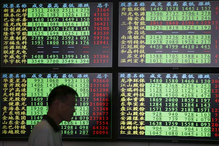 An investor walks past as information displayed on an electronic screen at a brokerage house in Shanghai