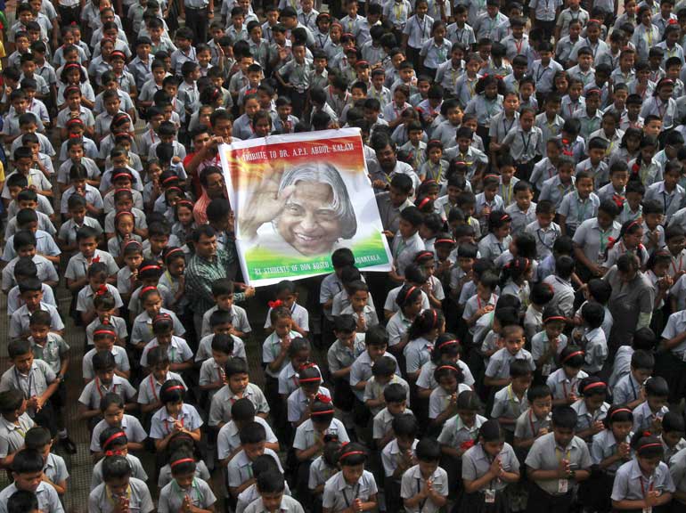 Teachers and schoolchildren hold a portrait of former Indian President Kalam during a prayer ceremony in Agartala
