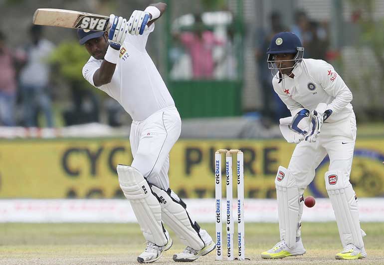 Sri Lanka's captain Mathews plays a shot next to India's wicketkeeper Saha during the first day of their first test cricket match in Galle