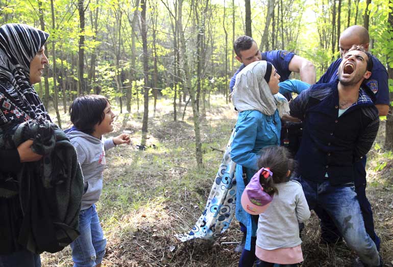 Hungarian policemen arrest a Syrian migrant family after they entered Hungary at the border with Serbia, near Roszke