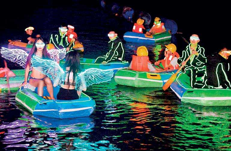 Tourists and models wearing LED-lit costumes take a night drifting tour at a eco-park in Changsha