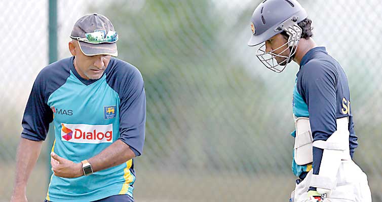 Sri Lanka's cricket coach Marvan Atapattu (L) advises team player Dinesh Chandimal during a practice session ahead of their third and final test cricket match against India in Colombo