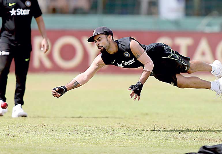 India's captain Kohli dives to catch the ball during a practice session ahead of their third and final test cricket match against Sri Lanka in Colombo