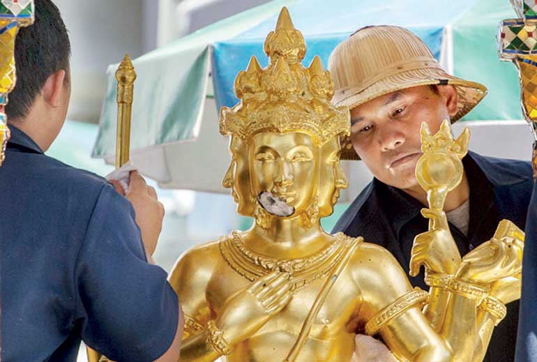 Workers clean a statue of Hindu god Brahma at the Erawan shrine, the site of a deadly blast in central Bangkok