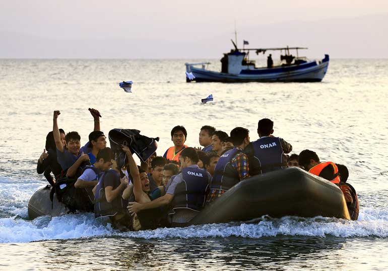 Jubilant Afghan migrants onboard an overcrowded dinghy arrive at a beach on the Greek island of Kos