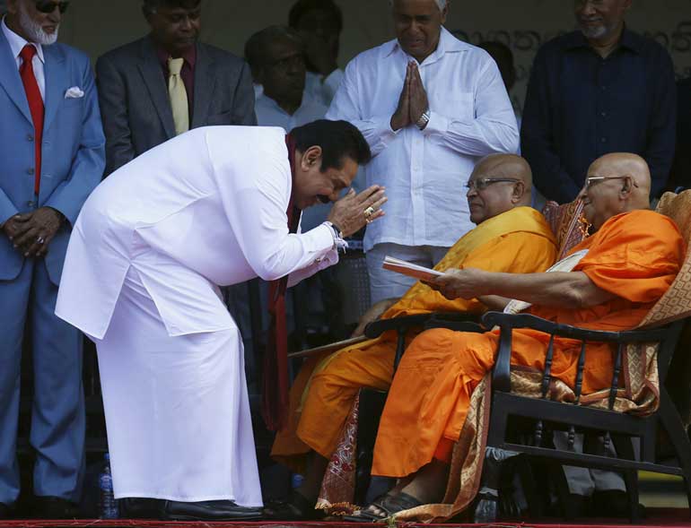 Sri Lanka's former president Mahinda Rajapaksa, who is contesting in the upcoming general election, hands over the first copy of his manifesto to a Buddhist monk, during the manifesto's launch ceremony, in Colombo