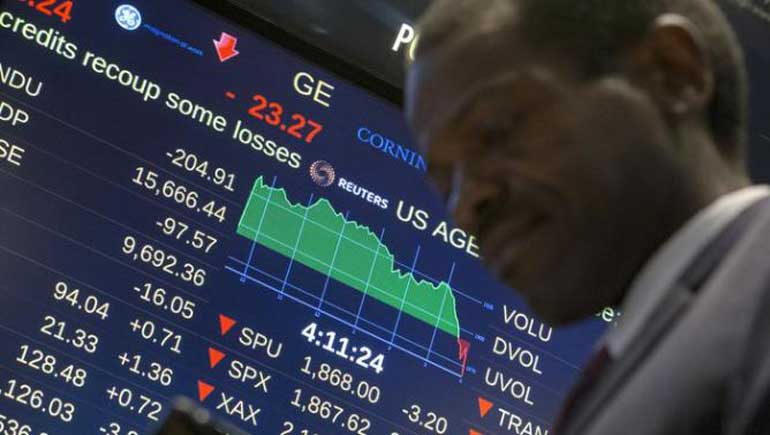 A screen displays the Dow Jones Industrial Average as a trader passes by on the floor after the closing bell at the New York Stock Exchange