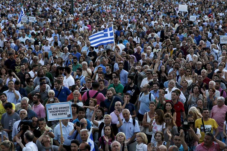 File photo of a man waving a Greek national flag as people rally outside the parliament in Athens