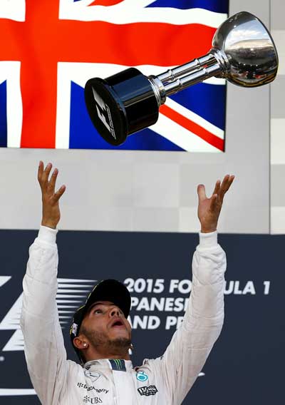 Mercedes Formula One driver Lewis Hamilton of Britain tosses his trophy into the air on the podium after winning the Japanese F1 Grand Prix at the Suzuka circuit in Suzuka