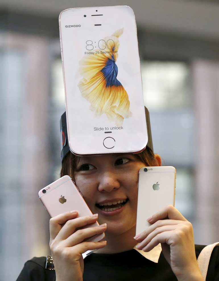 Japanese Makiko Maeda, 28, shows off her iPhone 6s after purchasing them at the Apple Store at Tokyo's Omotesando shopping district
