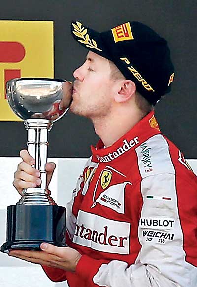 Third-placed Ferrari Formula One driver Sebastian Vettel of Germany kisses his trophy after the Japanese F1 Grand Prix at the Suzuka circuit in Suzuka, Japan