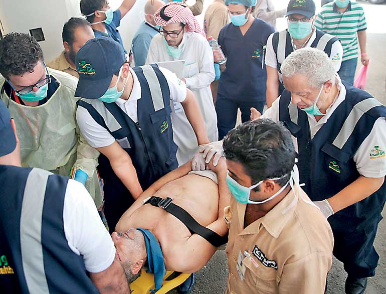 Medical staff carry a way wounded pilgrim following a crush caused by large numbers of people pushing at Mina, outside the Muslim holy city of Mecca