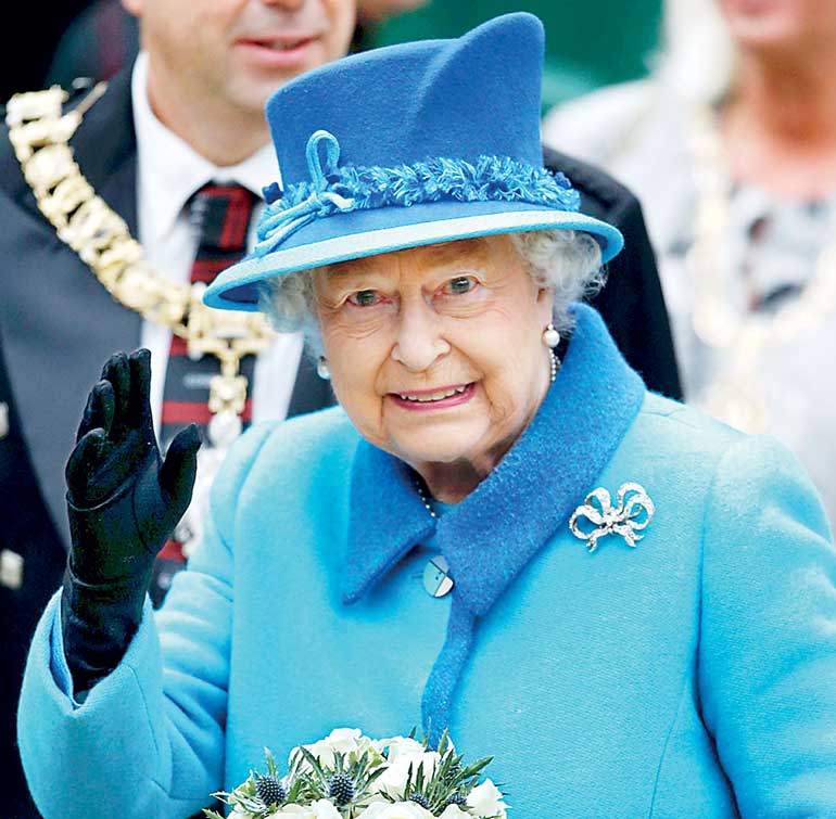 Britain's Queen Elizabeth waves as she arrives at Edinburgh Waverley Station before boarding a train drawn by a steam locomotive to travel along the Scottish Borders Railway in Scotland