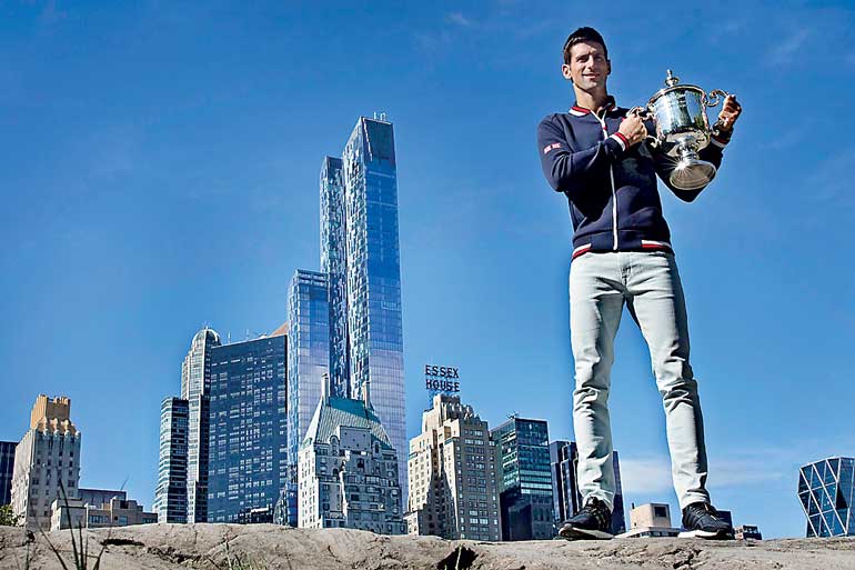 Novak Djokovic of Serbia poses with the champion's trophy in Central Park a day after winning the U.S. Open Championships men's tennis tournament in New York