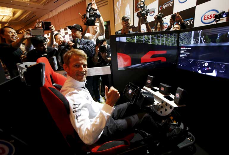 McLaren Formula One driver Jenson Button of Britain gestures before racing in a virtual simulator during publicity events ahead of the Singapore F1 night race in Singapore