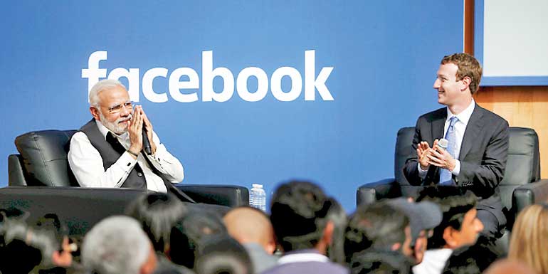 Indian Prime Minister Narendra Modi gives a "namaste" as Facebook CEO Mark Zuckerberg applauds on stage after a town hall at Facebook's headquarters in Menlo Park, California