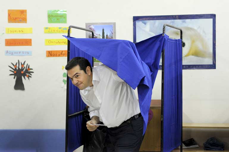 Former Greek prime minister and leader of leftist Syriza party Tsipras holds his ballot as he exits a voting booth during the general election at a polling station in Athens