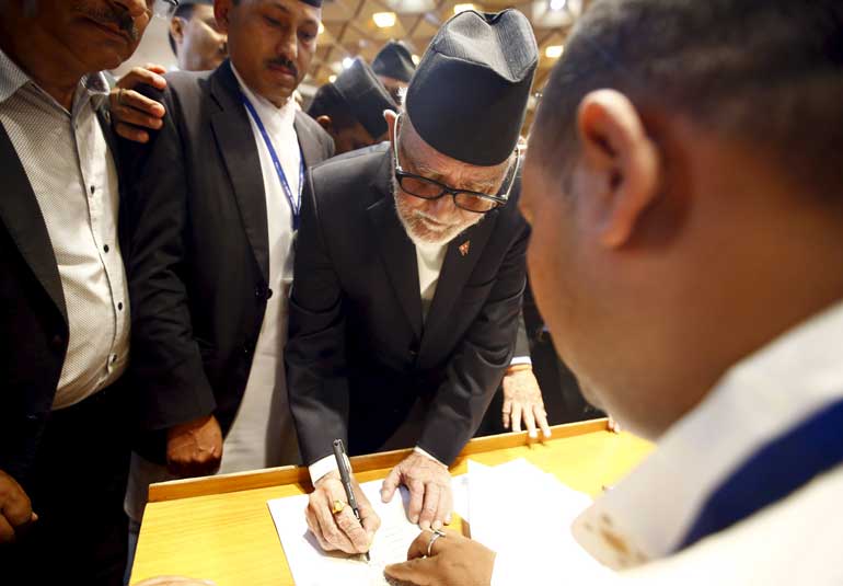 Nepalese Prime Minister Sushil Koirala signs on the copy of constitution at the parliament in Kathmandu