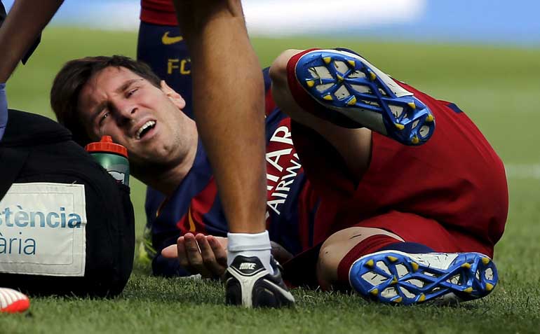 Barcelona's Messi grimaces as he lies on the pitch after injuring his left knee during their Spanish first division soccer match against Las Palmas  in Barcelona