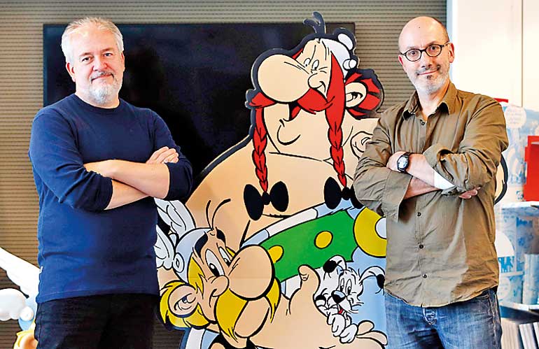 Author Jean-Yves Ferri and illustrator Didier Conrad pose next to cardboard cut-out of Obelix and Asterix in Vanves, Southern Paris