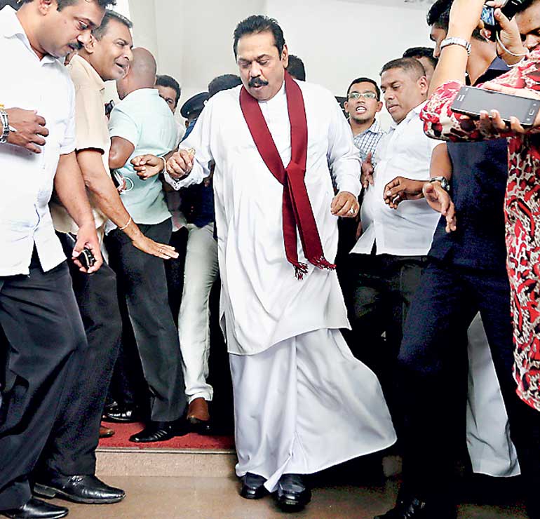 Sri Lanka's former president Rajapaksa reacts after taking a misstep as he left the Special Presidential Commission of Inquiry centre, in Colombo