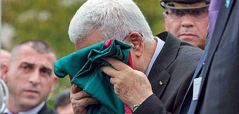 Palestinian President Mahmoud Abbas kisses a Palestinian flag before raising it during United Nations General Assembly at the United Nations in Manhattan, New York