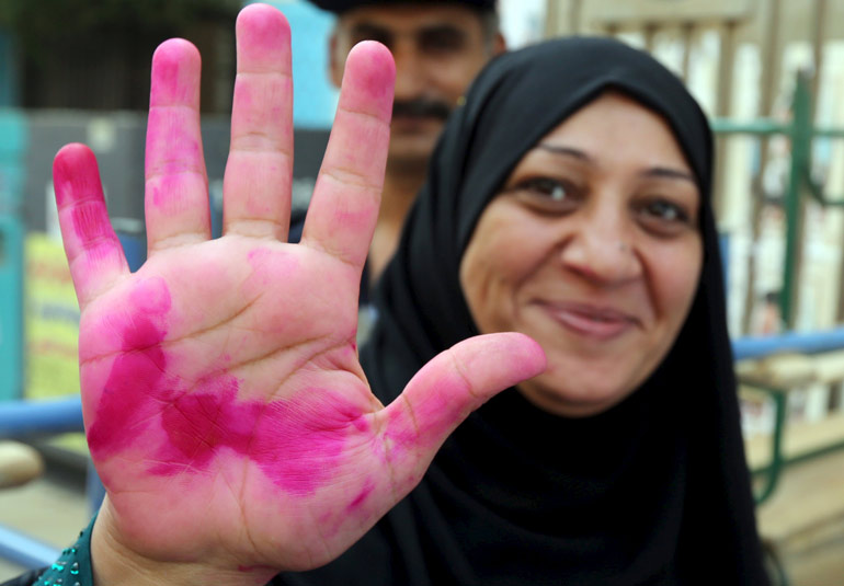 A woman shows the ink on her hand after voting during the first phase of the parliamentary elections at a polling station in Giza governorate