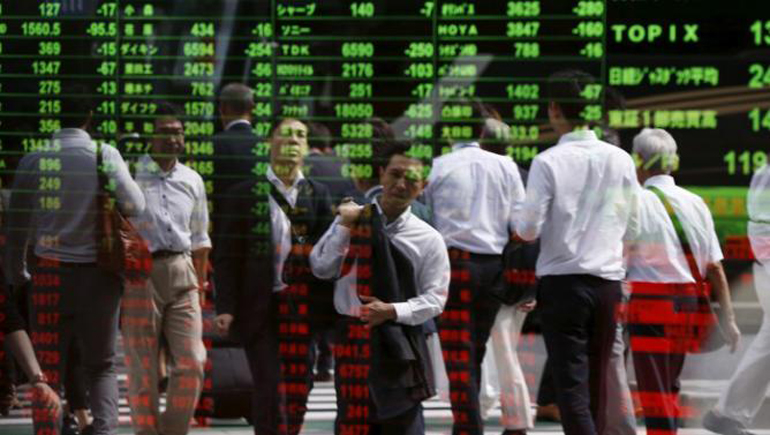 Passersby are reflected on a stock quotation board at a brokerage in Tokyo