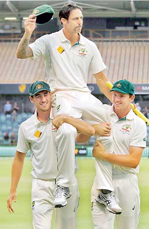 Australia's Johnson reacts as he is carried from the field by team mates Starc and Hazlewood at the end the fifth day of the second cricket test match against New Zealand at the WACA ground in Perth