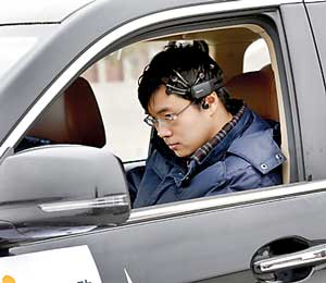 Researcher Zhang Zhao wearing a brain signal-reading equipment prepares to move a car with his brain wave, during a demonstration at Nankai University in Tianjin