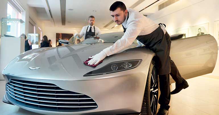 Employees polish an Aston Martin DB10 engineered by Aston Martin for the James Bond film "Spectre", during a media preview of "Spectre - the Auction" at Christie's auction house in London