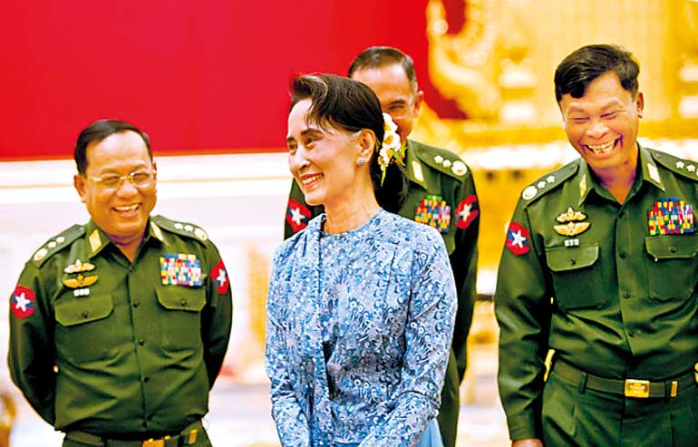 Myanmar's NLD party leader Aung San Suu Kyi smiles with army members during the handover ceremony of outgoing President Thein Sein and new President Htin Kyaw at the presidential palace in Naypyitaw