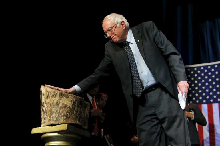 U.S. Democratic presidential candidate and U.S. Senator Bernie Sanders touches the "Tree of Hope" as he takes the stage for a campaign "Community Conversation" at the Apollo Theater in Harlem