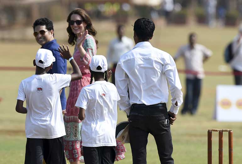 Catherine, Duchess of Cambridge, waves as she walks with former Indian cricketer Sachin Tendulkar as they meet with Indian children who are beneficiaries of NGOs at the Oval Maidan in Mumbai