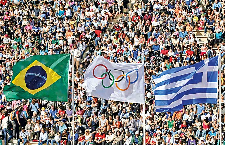 The Brazilian, Olympic and Greek flags fly over the Panathenaic Stadium during the handover ceremony of the Olympic Flame to the delegation of the 2016 Rio Olympics, in Athens